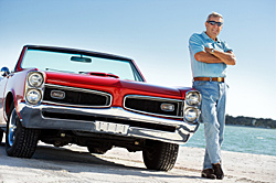 Photo of man standing beside a classic car